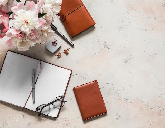 Lugar de trabajo plano para mujeres con organizador de bloc de notas de flores de peonía Concepto de negocio de vista superior de fondo claro