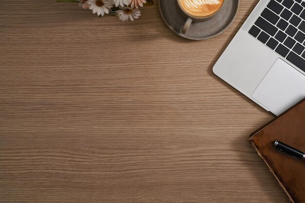 Lugar de trabajo simple con computadora portátil, taza de café, cuaderno y maceta