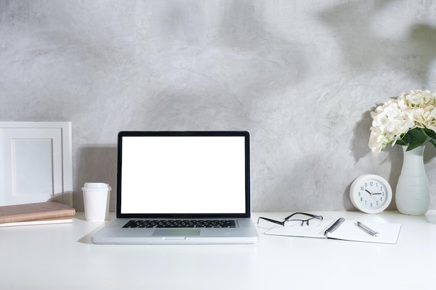 Lugar de trabajo simple con taza de computadora portátil de marco de imagen de café y planta de interior en mesa blanca