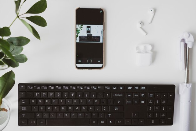 Lugar de trabajo con smartphonekeyboard y auriculares sobre fondo blanco.