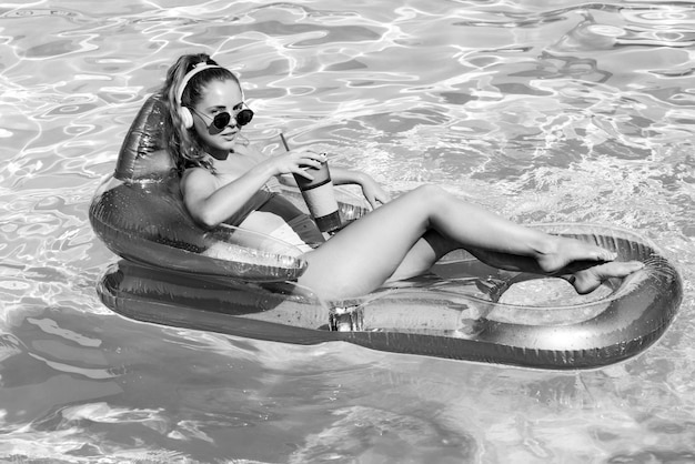 Lugar de veraneo. Mujer en traje de baño sobre colchón inflable en la piscina. Fin de semana de verano.