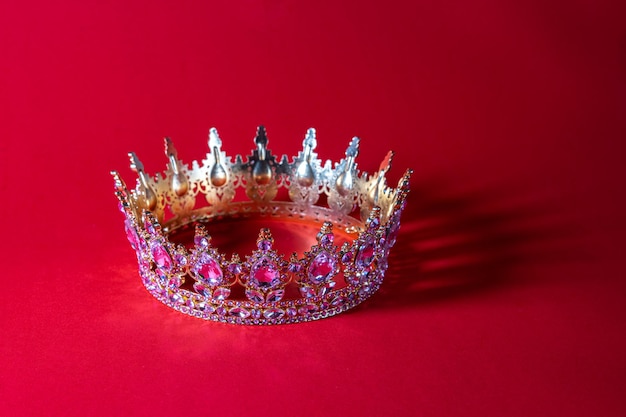 Una lujosa corona de oro con piedras preciosas brillantes sobre un fondo rojo