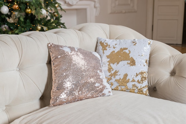 Lujosas almohadas de estilo clásico y brillante en un sofá beige Cojines decorativos de lentejuelas y ante beige en el sofá Decoración de la habitación para las vacaciones Preparación para el Año Nuevo y la Navidad