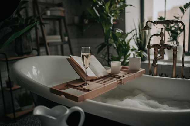 Lujoso interior de baño moderno de estilo ecológico con bañera ovalada y libro en bandeja de madera de bambú