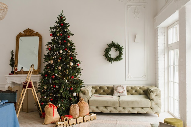 lujoso interior de la sala de estar en un estilo clásico sofá árbol de Navidad con regalos junto a la chimenea