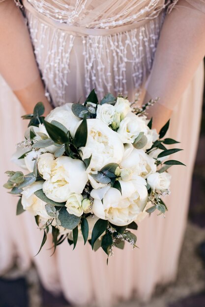 Lujoso ramo blanco de peonías y rosas en manos de la novia