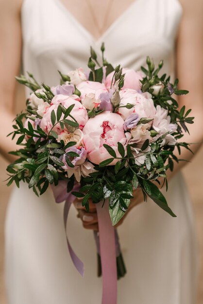 Un lujoso ramo de novia con peonías rosas en manos de la novia