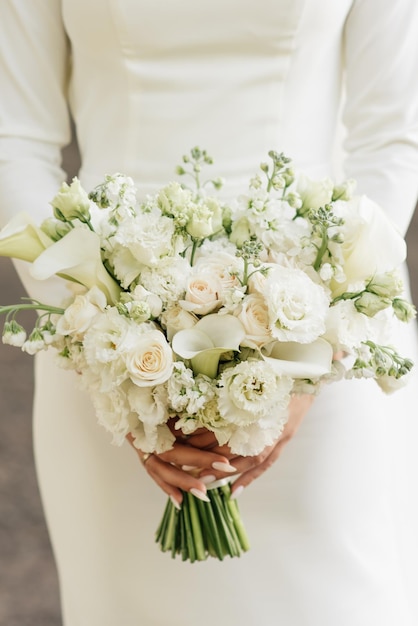 Un lujoso ramo de novia con rosas blancas, claveles y koalas en manos de la novia