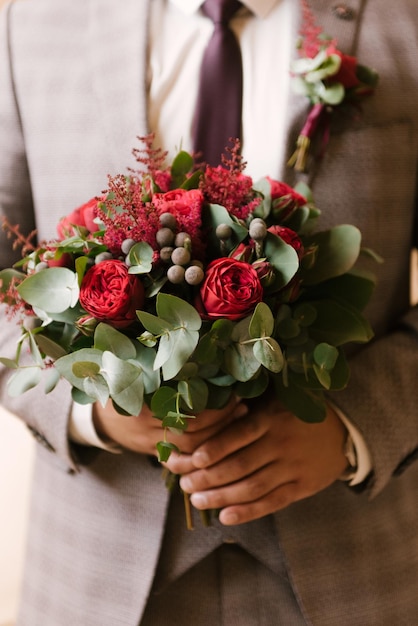 Un lujoso ramo de novia con rosas rojas en manos de la novia