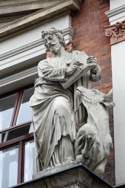 Lukas, der Evangelist, mit einer Stierstatue an einer Ziegelsteinmauer