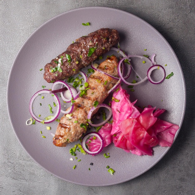 Lula kebab de cerdo y ternera con col en escabeche y vista superior de cebolla roja
