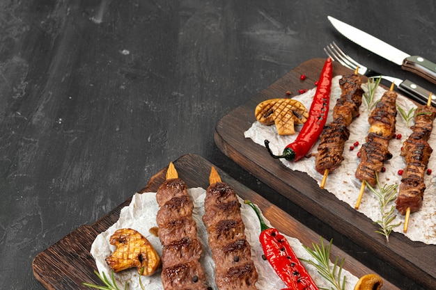 Lula kebab a la parrilla en brochetas servidas sobre tabla de madera
