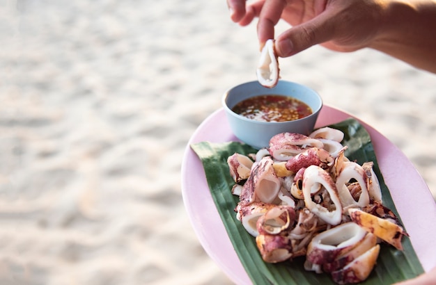 Lulas grelhadas no mar da praia - fatia de lula na chapa com molho de frutos do mar tailandês por lado