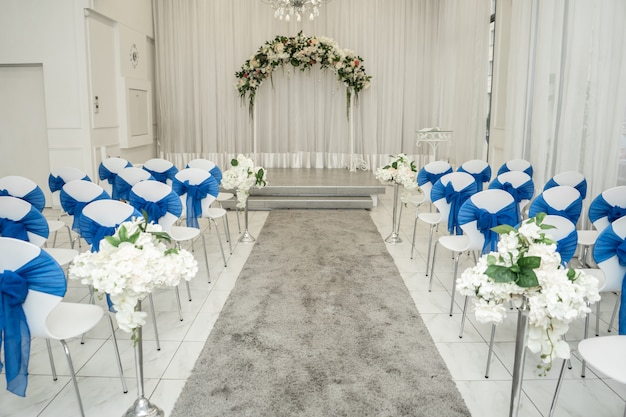 Luminoso salón para bodas. Filas de sillas de invitados decoradas con tela azul