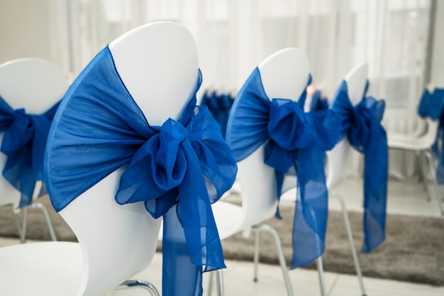 Luminoso salón para bodas. Filas de sillas de invitados decoradas con tela azul