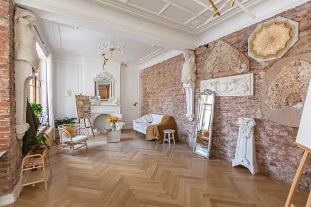 Luminoso salón taller para la creación y obra de un arquitecto y artista en estilo loft con paredes de ladrillo y parquet. las paredes están decoradas con ejemplos de estuco.