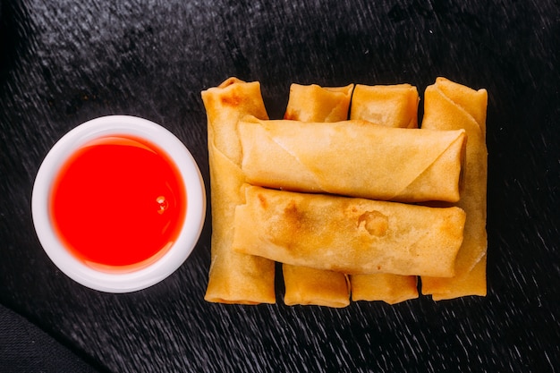 Lumpias com molho doce em fundo preto