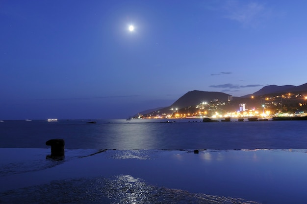 Luna ascendiendo sobre el mar Negro en lugar de la ciudad de Alushta en Crimea, Ucrania