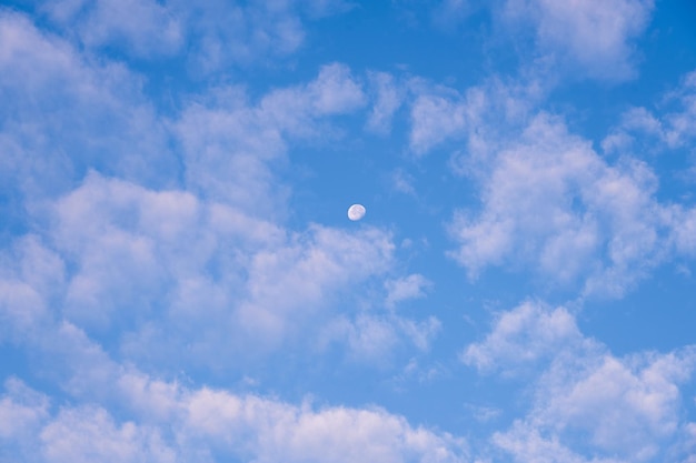 La luna en el cielo azul entre las nubes es como un fondo.