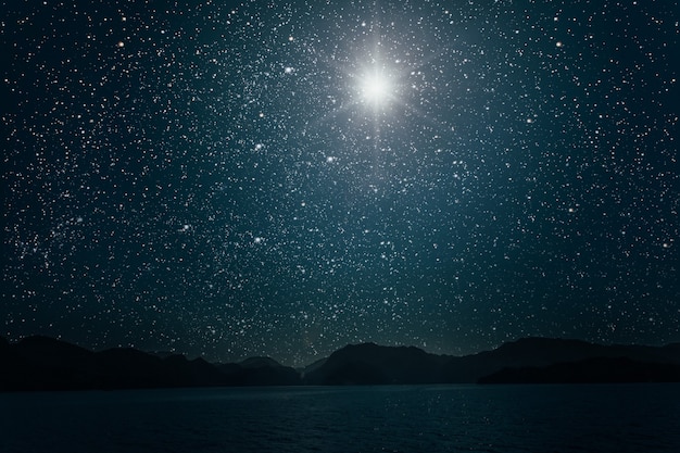 Luna contra un cielo estrellado nocturno brillante reflejado en el mar.