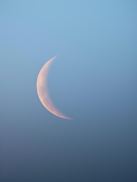 una luna creciente es visible en el cielo azul.