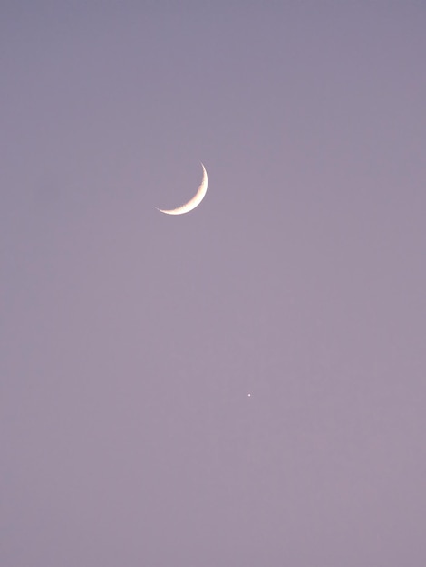 Luna creciente y una estrella en el cielo vacío sin nubes por la noche