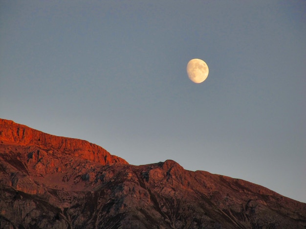 La luna se esconde detrás de las montañas al atardecer Dolomitas Italia