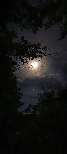 Foto una luna llena está brillando a través de las nubes y la luna está brillando en las nubes