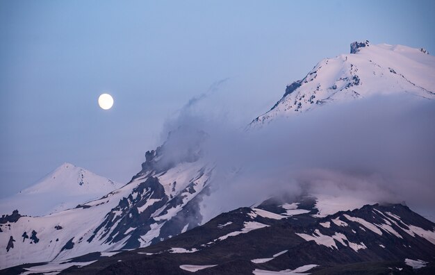 Luna llena dorada elevándose sobre montañas distantes en la hora azul