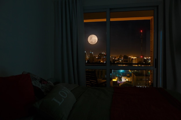 Foto luna llena vista a través del vidrio de la ventana en el dormitorio