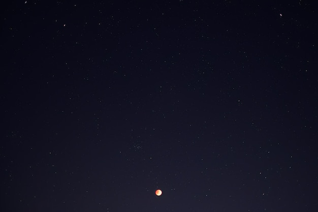 Luna de sangre del eclipse lunar con estrellado en el cielo nocturno