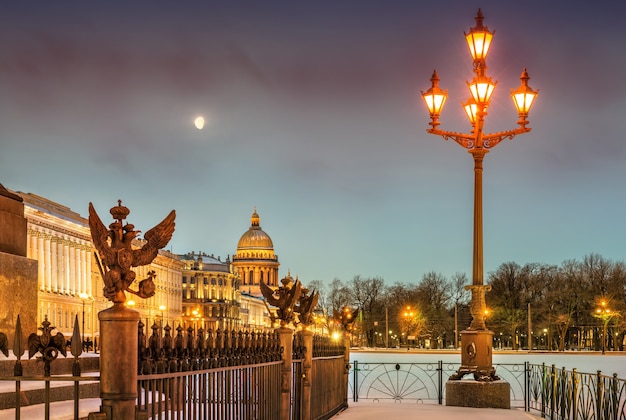 Luna sobre la Catedral de San Isaac y la linterna de la Plaza del Palacio en una mañana de invierno en San Petersburgo