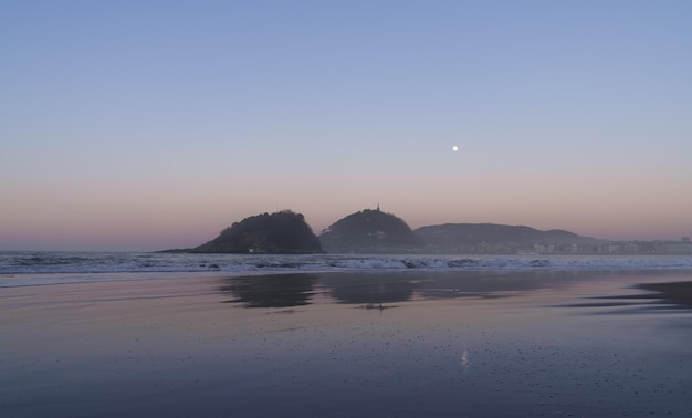 Foto luna sobre la playa de ondarreta en la bahía de concha en la ciudad de donostia san sebastián