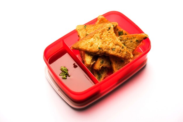 Foto lunch box o tiffin para niños indios, incluye tortilla de pan pakora con ketchup o brotes, enfoque selectivo