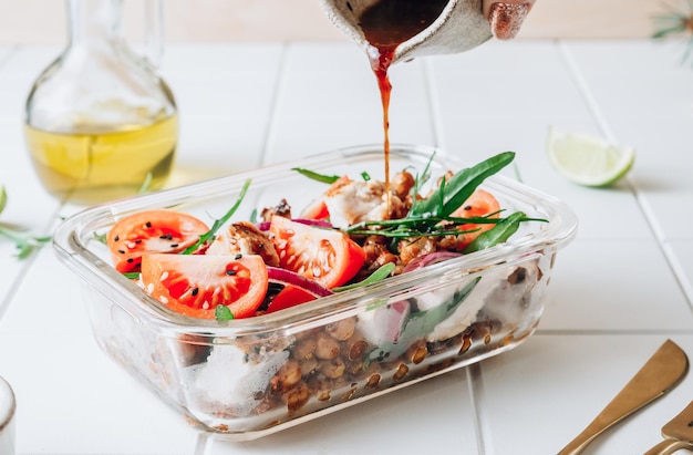 Lunchpaket mit warmem Salat mit gegrilltem Hähnchen, würzigen Kichererbsen, Tomaten und Rucola