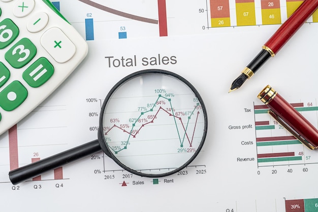 Lupa y bolígrafo en gráficos de gráficos financieros