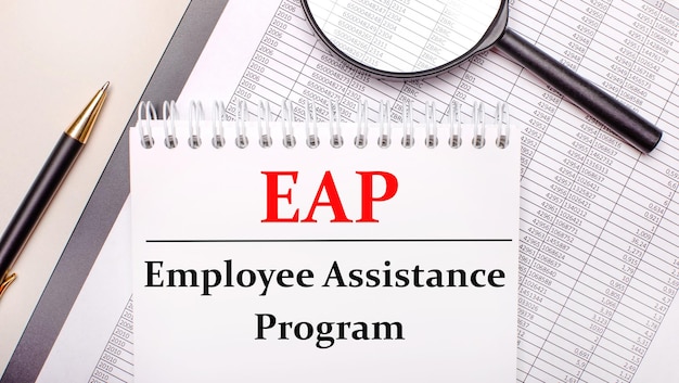 Lupa de mesa, relatórios, caneta e caderno com texto EAP Employee Assistance Program