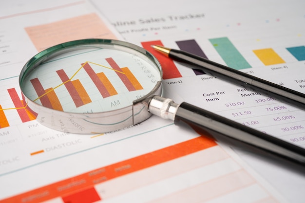 Lupa en papel de gráficos de gráficos. Desarrollo financiero, cuenta bancaria, estadísticas, economía de datos de investigación analítica de inversiones, comercio de bolsa, concepto de reunión de empresa de oficina de negocios.