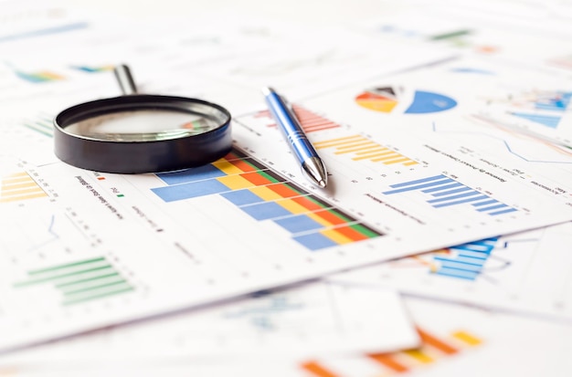 Lupa y pluma en gráficos de gráficos financieros Informe de documento anual