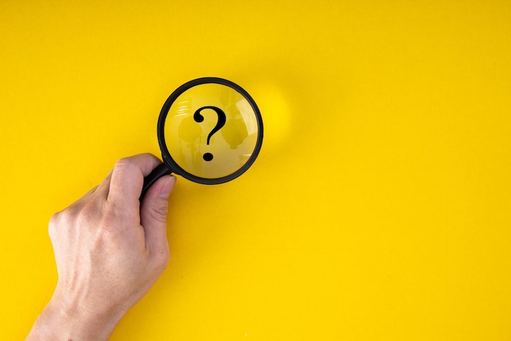 Foto lupa con signo de interrogación en foco sobre fondo amarillo