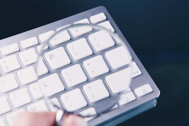 Lupa y teclado blanco sobre la mesa