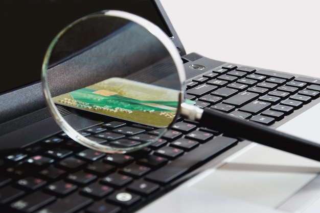 Una lupa de vidrio se encuentra en el teclado junto con una tarjeta bancaria en un lugar de trabajo acogedor