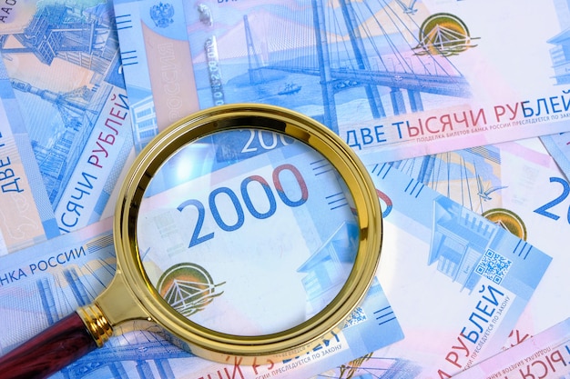 Lupe gegen den Hintergrund Russische Rubel mit Nennwert zweitausend