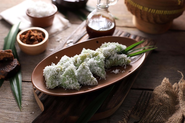 Lupis, refrigerio tradicional indonesio elaborado con arroz pegajoso, envuelto en hojas de plátano, en forma de triángulo, servido con azúcar de palma líquida y coco rallado