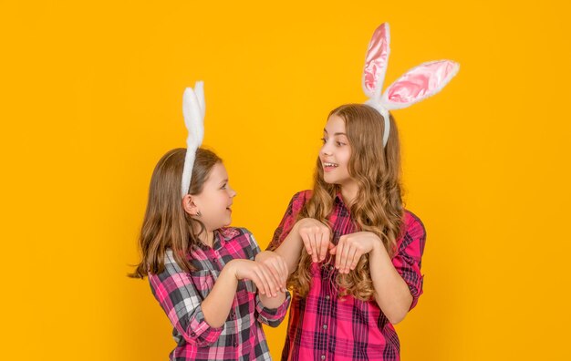 Lustig erstaunte Osterkinder in Hasenohren auf gelbem Hintergrund