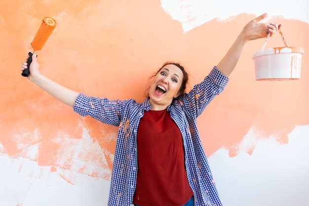 Lustige Frau, die Wand in ihrer neuen Wohnung malt