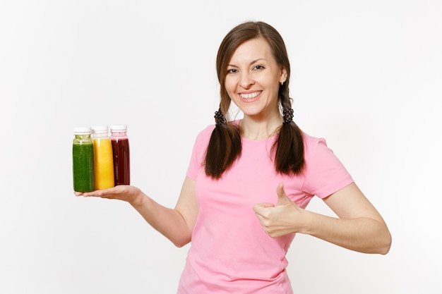 Lustige Frau hält eine Reihe von grünen, roten, gelben Detox-Smoothies in Flaschen auf weißem Hintergrund. Richtige Ernährung, vegetarisches Getränk, gesunder Lebensstil, Diätkonzept. Kopieren Sie Platz für Werbung.