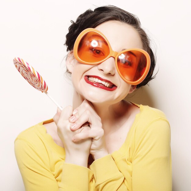 Lustige Frau mit großer heller Sonnenbrille mit Lutscher