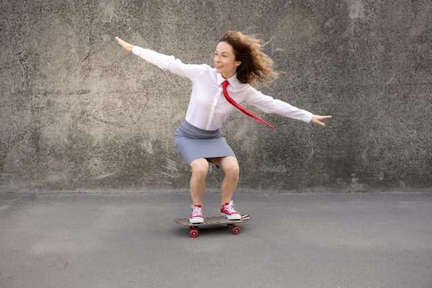 Lustige Geschäftsfrau, die im Freien Skateboard reitet