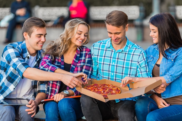 Foto lustige junge studenten essen pizza.